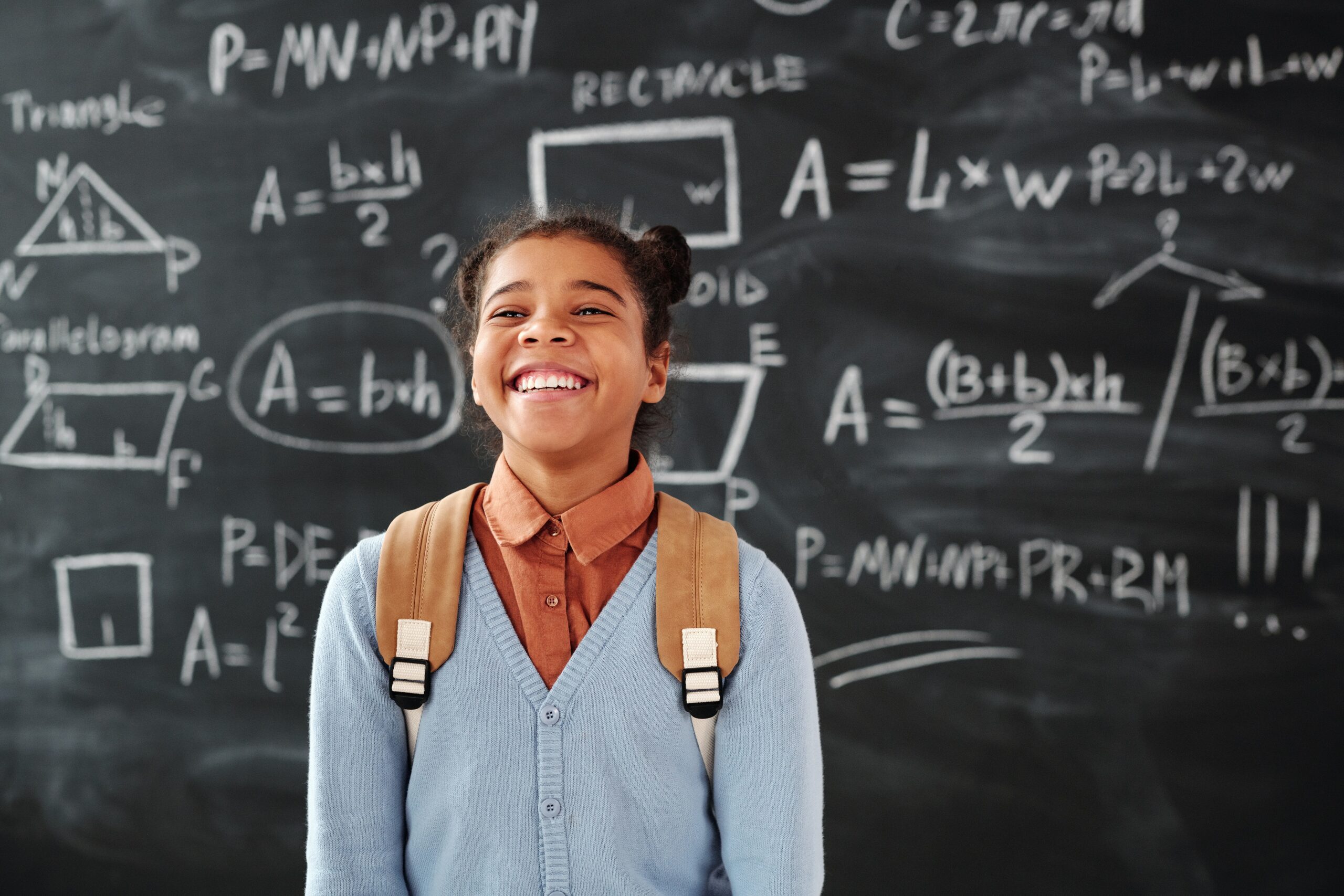 student smiling next to a blackboard